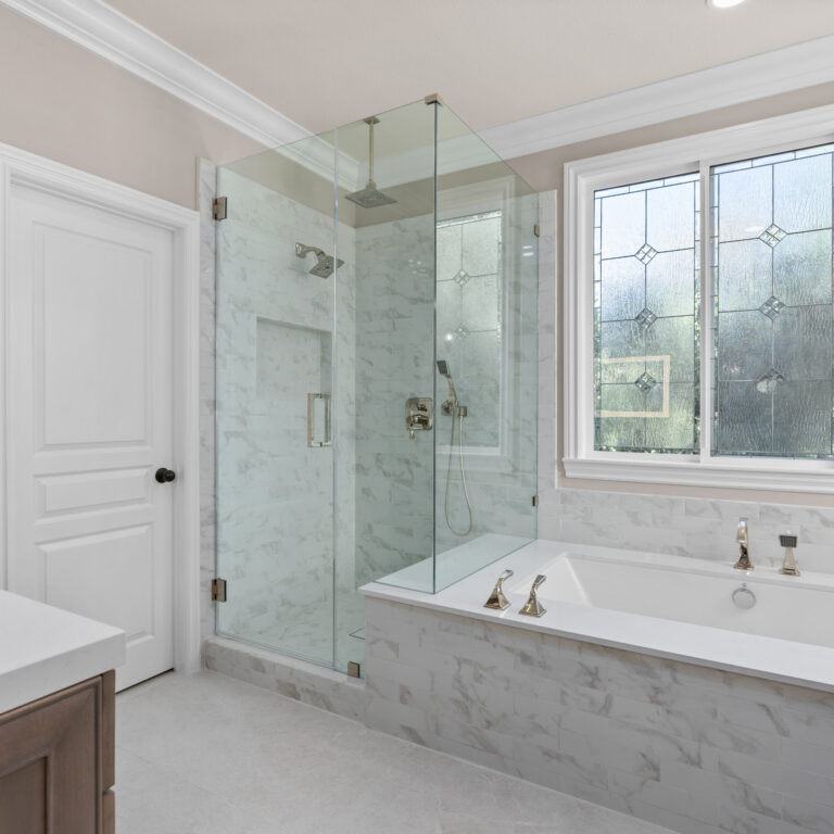 Elegant traditional bathroom remodel with soaking tub, glass shower enclosure, and custom dark wood vanity in San Clemente.