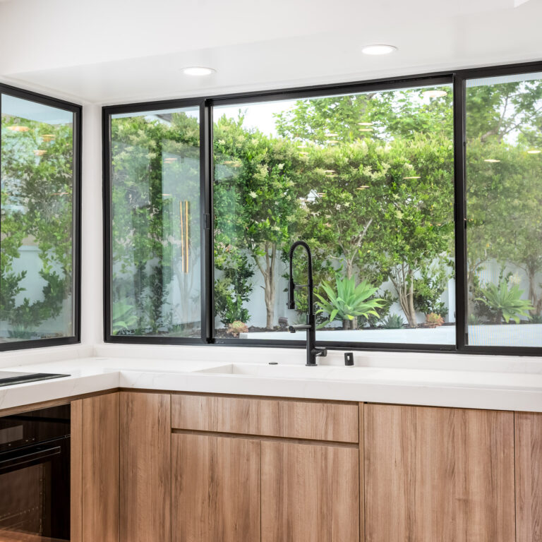 Custom kitchen sink with integrated quartz basin and flat-panel natural wood cabinets in Newport Beach.